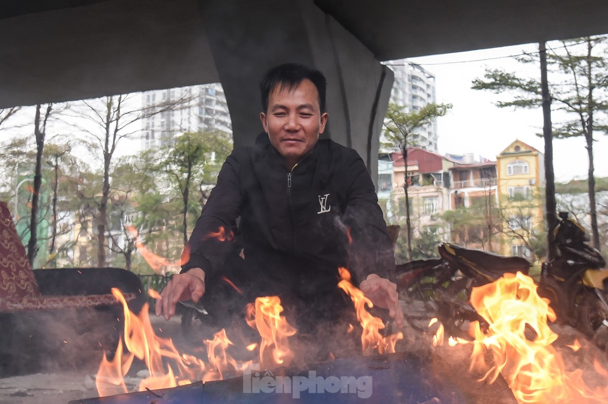 Some people keep warm by lighting a fire on the sidewalk.