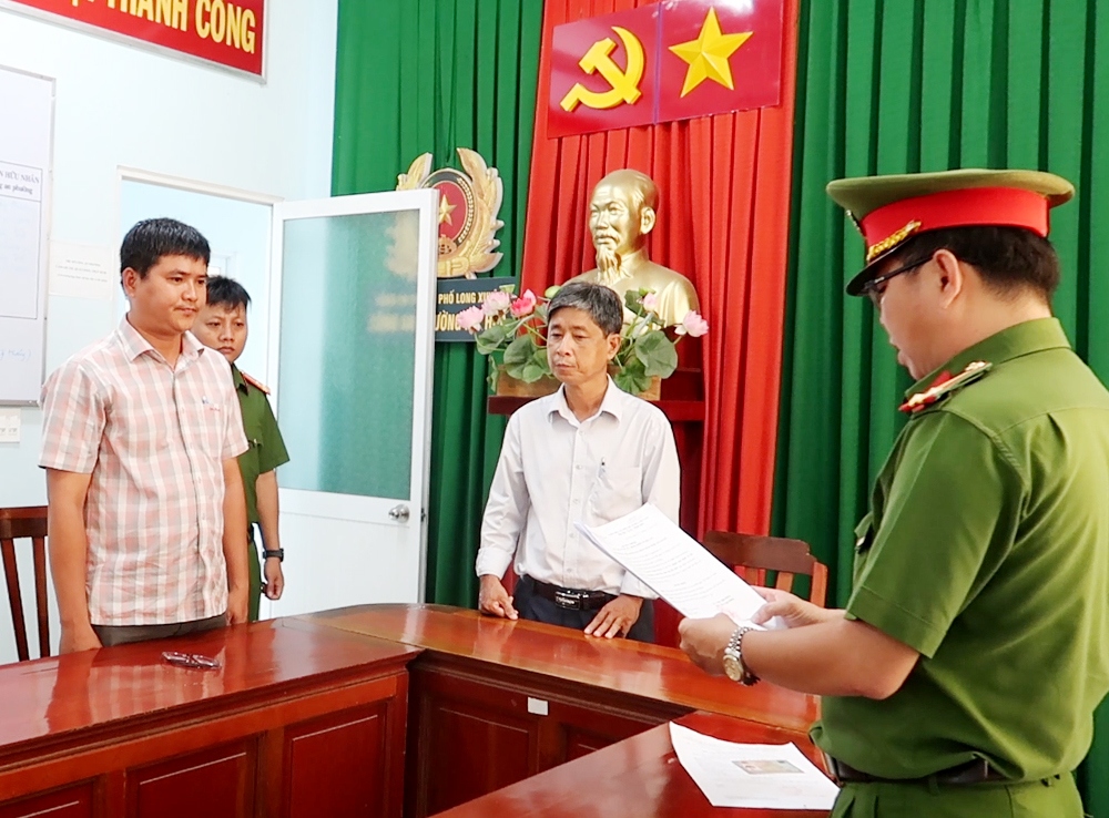 Lực lượng chức năng tống đạt các quyết định khởi tố, bắt tạm giam và khám xét nơi ở và nơi làm việc đối với Nguyễn Thanh Phong (áo sọc).