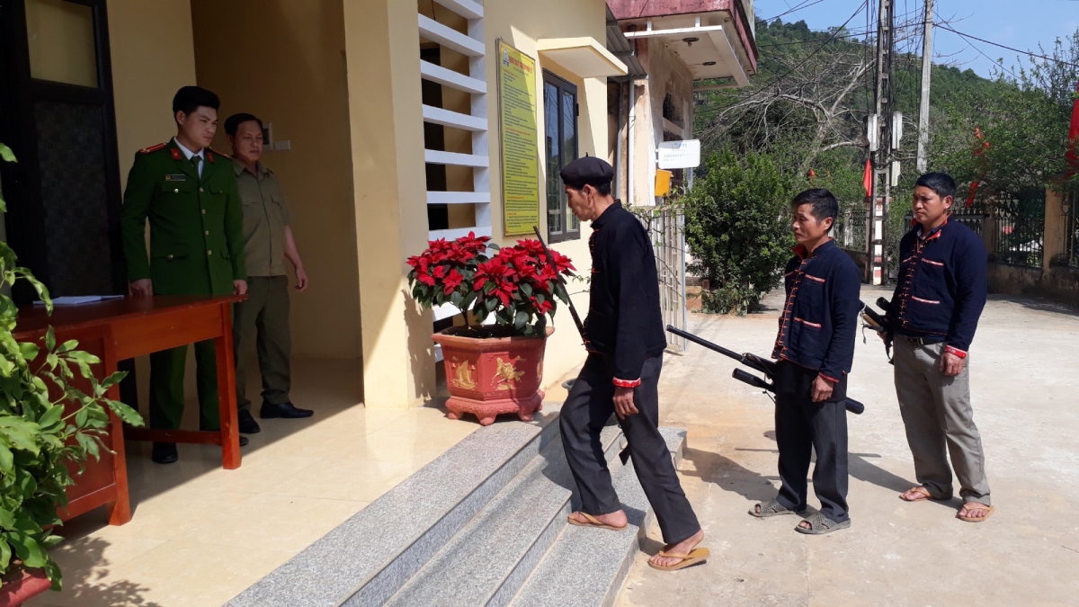Ông Hoàng Quý Chìu (người đi đầu tiên) mang khẩu súng kíp gắn bó lâu năm nộp cho Công an xã.