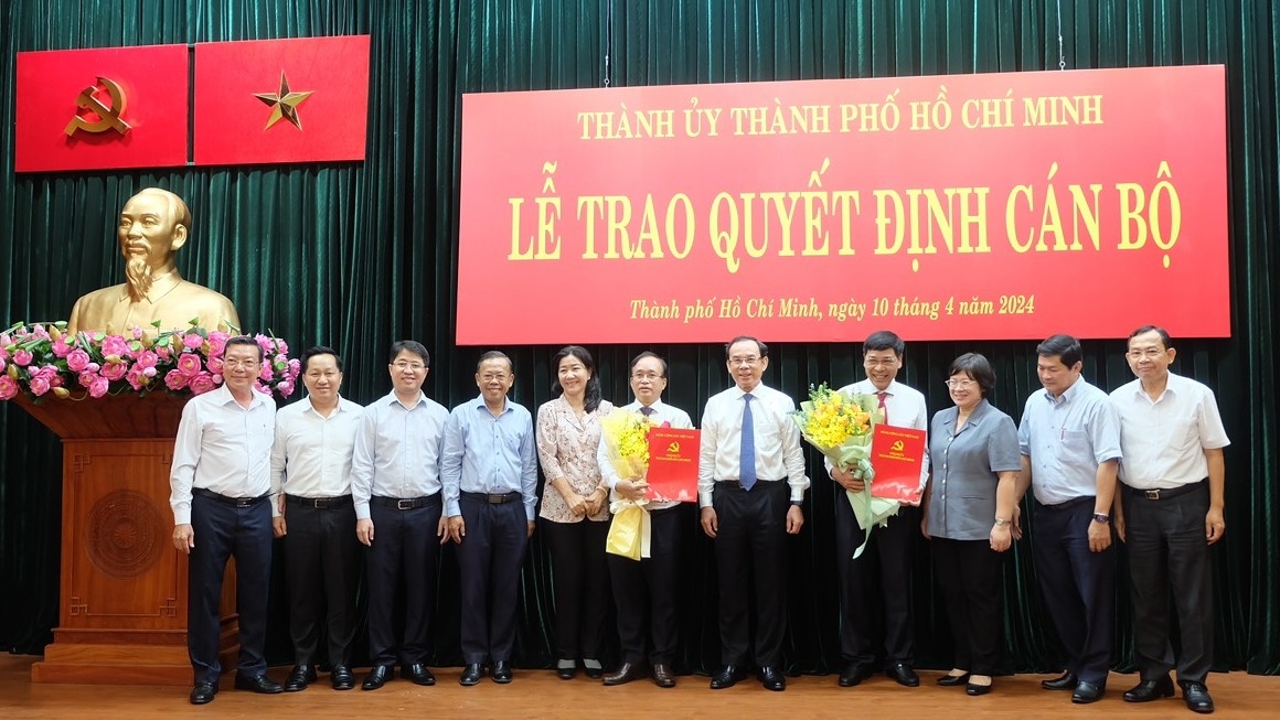 Bí thư Thành ủy Nguyễn Văn Nên và lãnh đạo các địa phương chụp hình chung với hai cán bộ được điều động (ảnh T.L)
