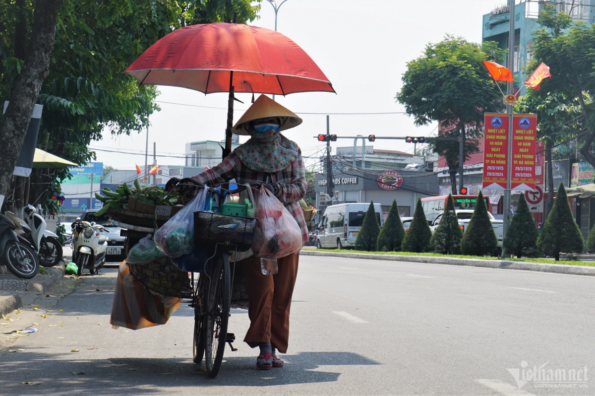 A street vendor dons a face mask and puts on long clothing to minimise the impact of the heat.