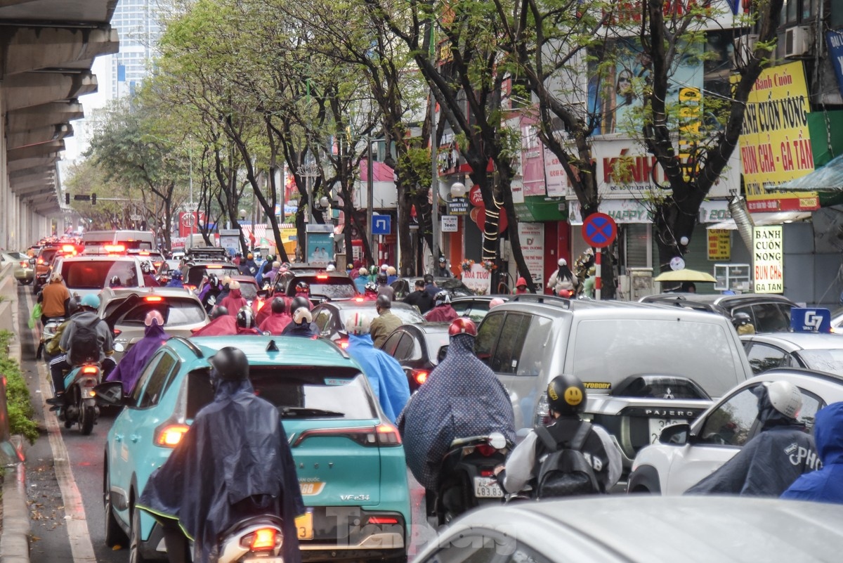 At 8 a.m. on Xuan Thuy street, people must wrap themselves up to cope with the chilly weather and downpour.