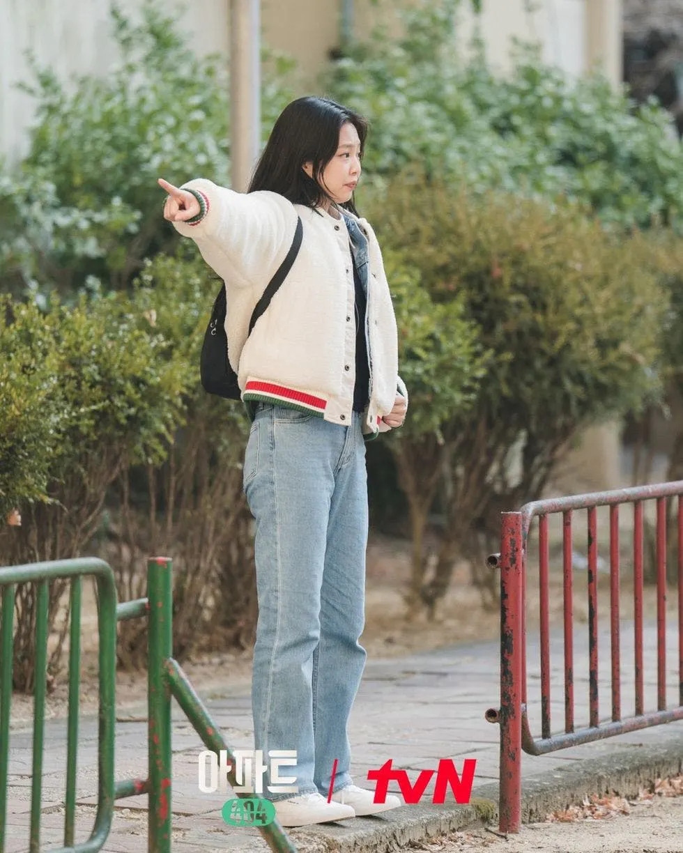 Khi nhiệt độ giảm xuống, Jennie khoác một chiếc áo khoác cotton trắng bên ngoài bộ quần áo denim đơn giản, không chỉ đảm bảo sự ấm áp mà còn tạo điểm nhấn cho trang phục của cô thông qua việc phối lớp một cách chiến lược. Vì chương trình “Apartment” 404 lấy bối cảnh của những thập niên trước nên những bộ trang phục được Jennie diện trong chương trình đều mang một chút nét cổ điển và đơn giản.Trong Apartment 404, Jennie rất ưu ái những chiếc quần jeans bó sát để có thể dễ dàng tôn lên đôi chân “triệu đô” của cô nàng. Bộ trang phục càng cổ điển hơn khi kết hợp cùng một chiếc sơ mi trắng đơn giản nhưng không đơn điệu giúp Jennie thêm phần trẻ trung, năng động nhưng cũng không kém phần thanh lịch.