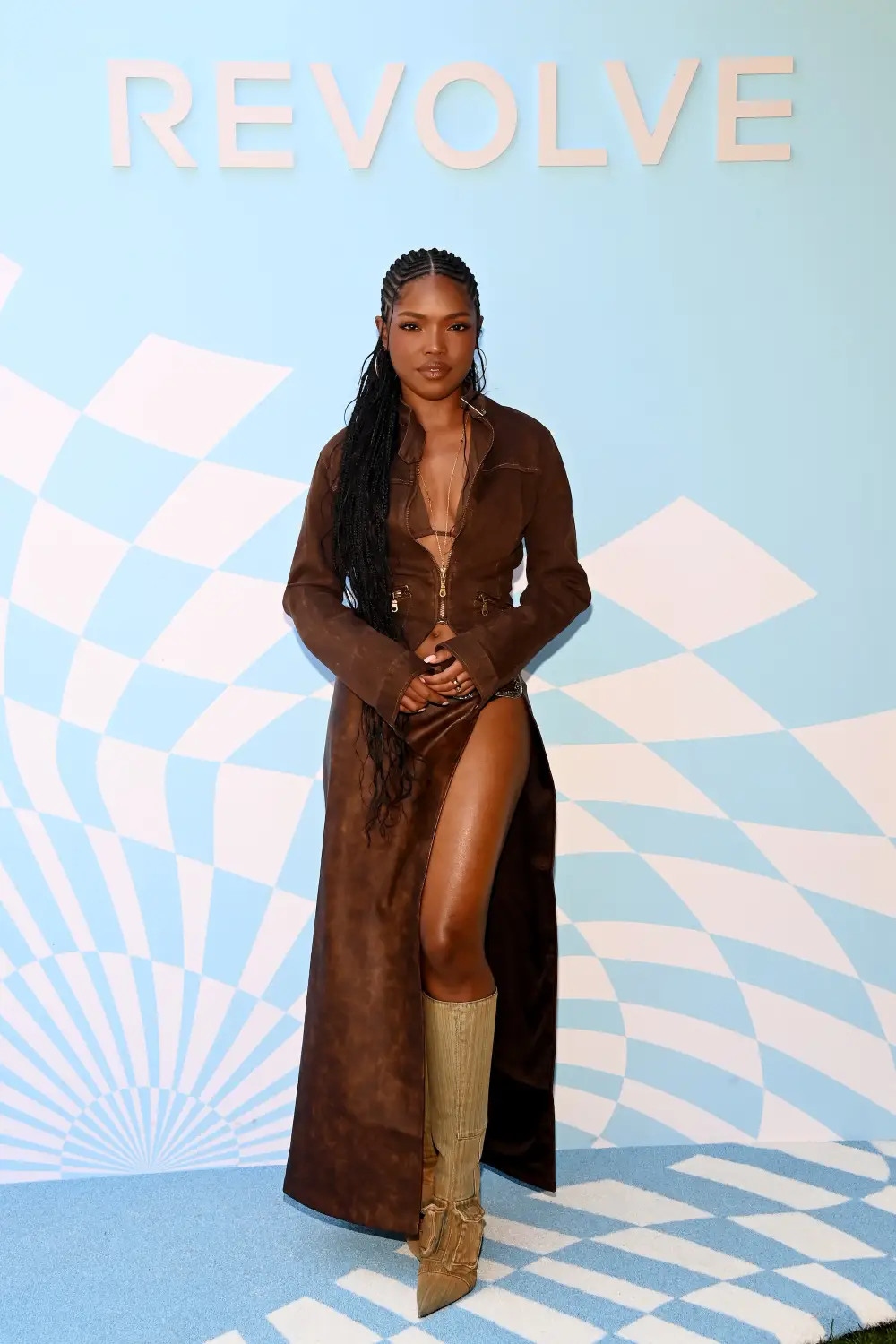Diễn viên "Star" Ryan Destiny đã chọn bộ quần áo màu nâu đơn sắc cho Revolve Fest, cô kết hợp với đôi bốt vàng dài tới đầu gối. Một chiếc áo bikini nằm bên dưới áo khoác mà cô ấy chỉ kéo khóa ở giữa, và chiếc váy cạp cao có đường cắt ấn tượng dài đến tận hông.