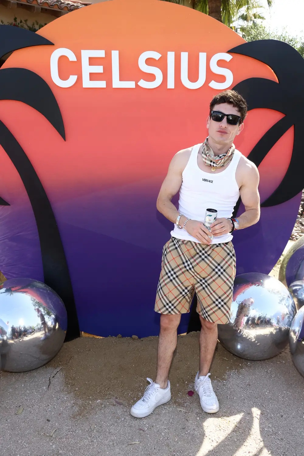 Bộ trang phục Coachella của Keoghan bao gồm áo ba lỗ họa tiết Versace, quần short kẻ sọc Burberry và khăn rằn phối hợp. Anh phối hợp với giày thể thao màu trắng đơn giản.