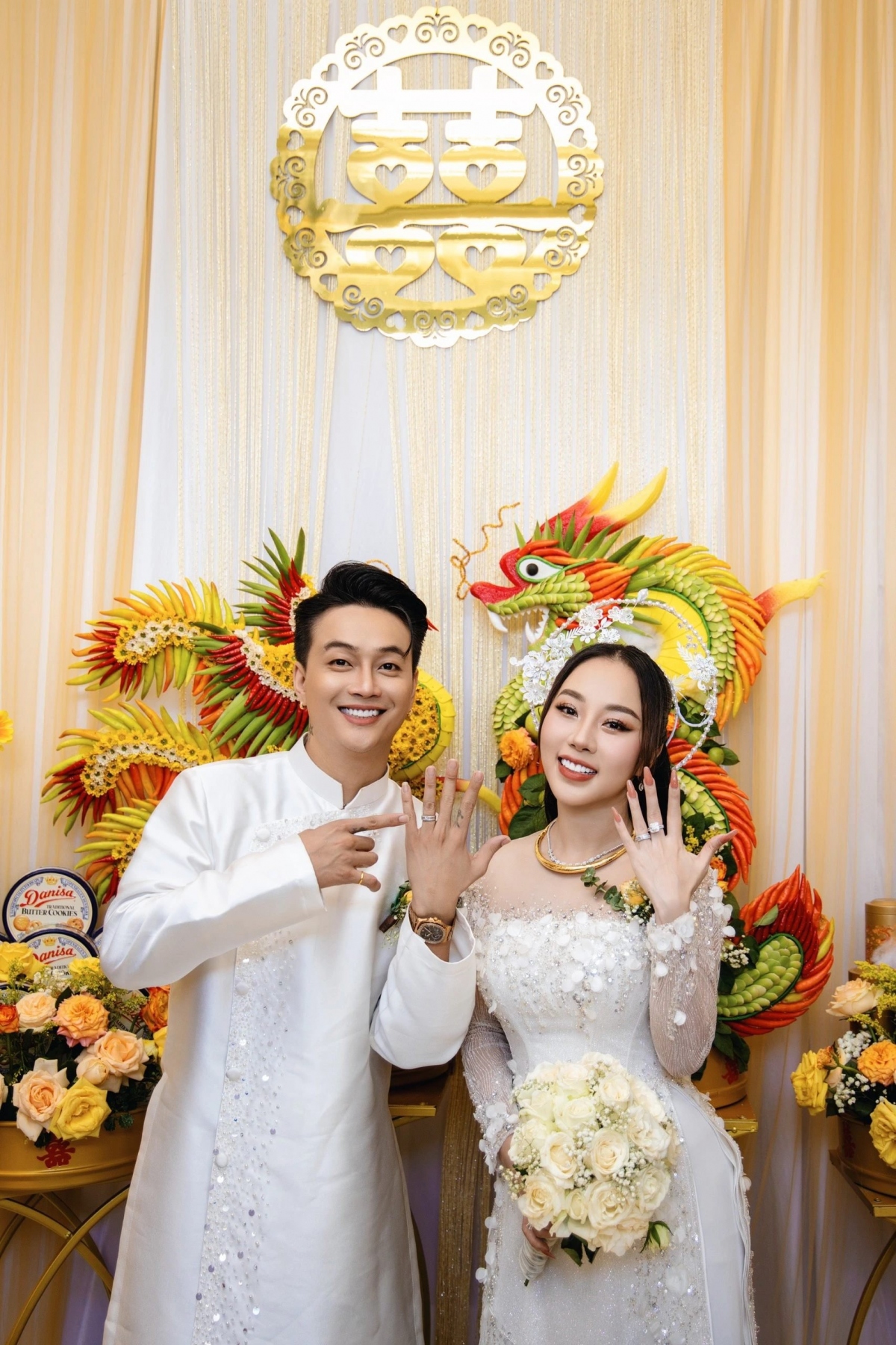 Lễ vu quy của ca sĩ Ti Ti (nhóm HKT) và cô dâu Tuyết Nhung diễn ra vào hôm nay (20/4) tại Cần Thơ. Ngày trọng đại của cặp đôi đã thu hút sự quan tâm của đông đảo người dân gần nhà cô dâu và người hâm mộ nam ca sĩ. Không gian tiệc trang trí bằng hoa tươi, nổi bật với lễ vật khắc hình rồng phượng. Quản lý của ca sĩ Ti Ti (nhóm HKT) tiết lộ, quà cưới từ mẹ ruột nam ca sĩ tặng cho hai con gồm: ba cây vàng 9999; tiền mặt 10.000 USD; lắc tay, nhẫn và hoa tai kim cương. Ngoài ra, vợ chồng nam ca sĩ nhận được quà cưới từ nhà gái gồm: hai cuốn sổ đỏ, tiền mặt 10.000 USD và hai trăm triệu đồng... (Nguồn: Dân Trí)