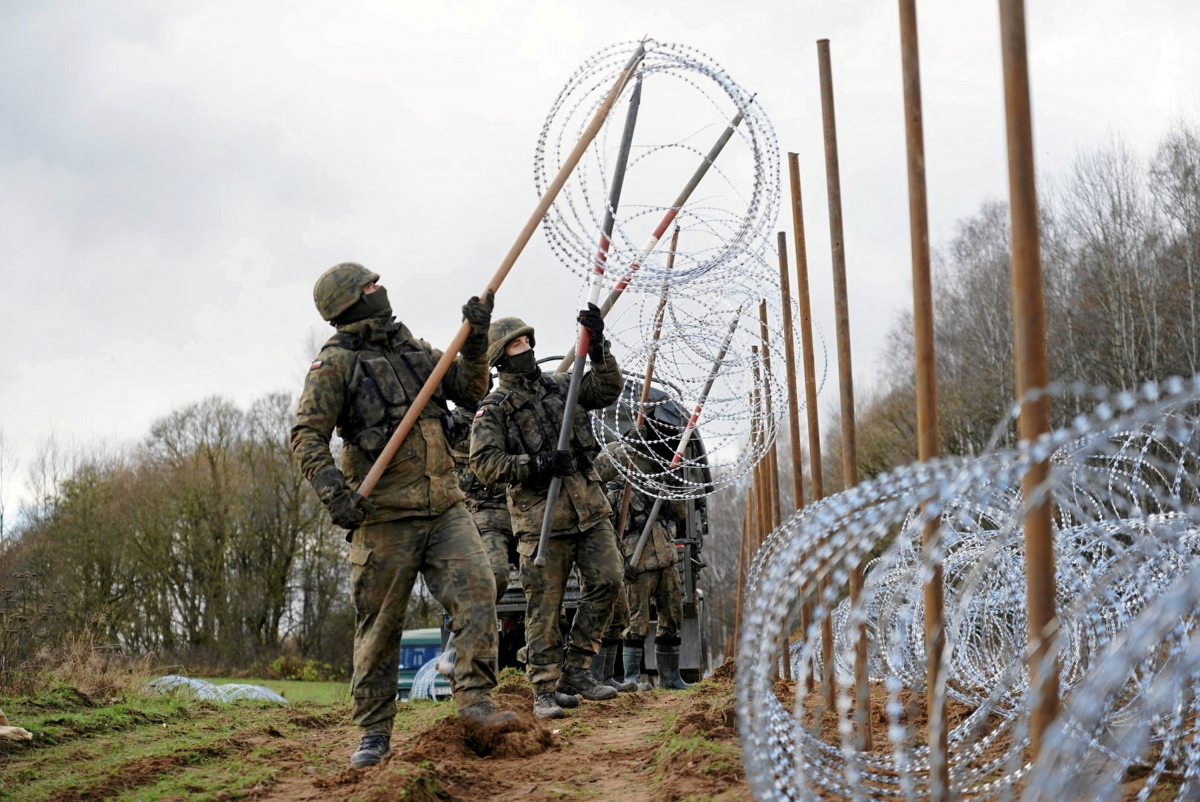 Các binh lính chăng hàng dây thép gai lên hàng rào ở biên giới giữa Ba Lan và vùng lãnh thổ Kaliningrad của Nga. Ảnh: Reuters