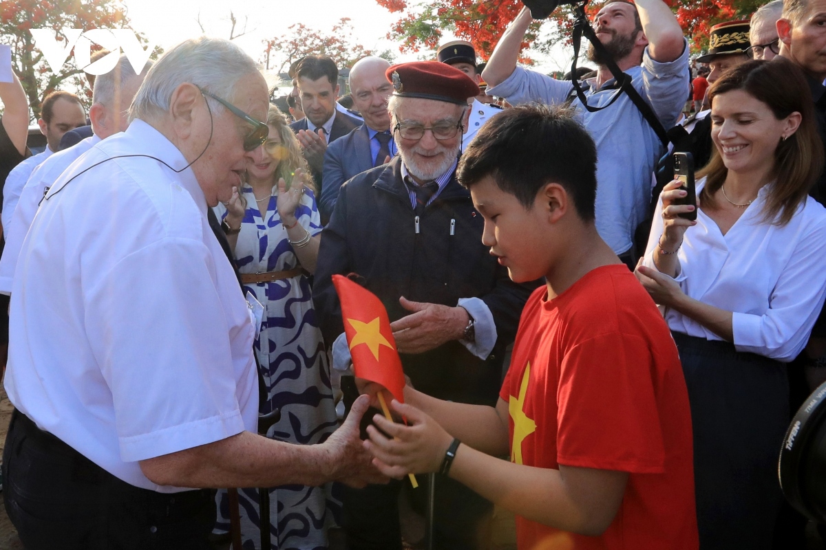 Ngo Tuong Minh, a 12-year-old student, performs the song “Hello Vietnam” and presents the Vietnamese flag to a French war veteran who fought at Dien Bien Phu seven decades ago.