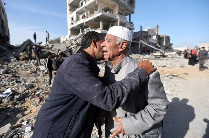 Hai người đàn ông Palestine trao nhau cái ôm trước ngôi nhà bị phá hủy do chiến tranh ở thành phố Khan Younis, sau khi lệnh ngừng bắn trong bốn ngày có hiệu lực ở Dải Gaza vào sáng 24-11 - Ảnh: Reuters