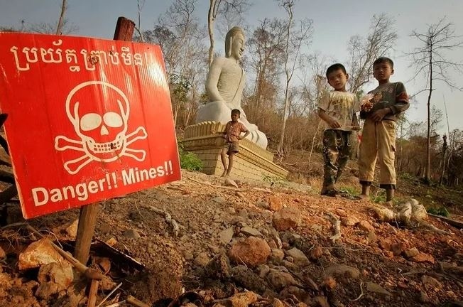 Trẻ em chơi gần một biển cảnh báo bom mìn ở khu vực biên giới Campuchia với Thái Lan. Ảnh: AP