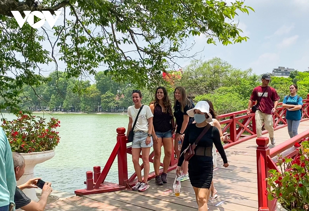 A group of foreign visitors take a photo at The Huc bridge, a tourist destination in Hanoi capital.