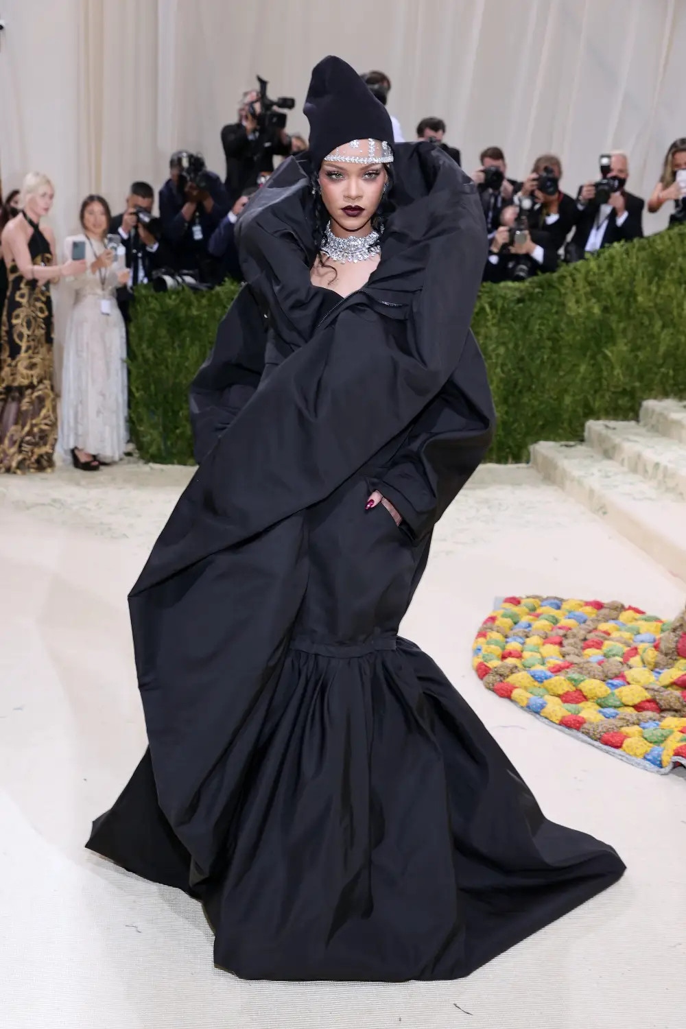 Rihanna đã diện bộ váy áo khoác thời trang cao cấp với tư cách là một trong những người nổi tiếng cuối cùng đến Met Gala 2021. Người sáng lập Fenty mặc chiếc áo khoác Balenciaga thời trang cao cấp do giám đốc sáng tạo Demna Gvasalia thiết kế. Rihanna kết hợp vẻ ngoài với một chiếc mũ len, vòng cổ kim cương và một chiếc mũ đội đầu bằng pha lê tuyệt đẹp. 