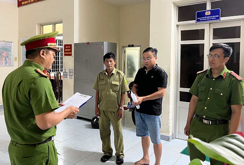 Cơ quan điều tra tống đạt quyết định khởi tố bị can và lệnh bắt tạm giam bị can Nguyễn Phú Hộ. (Ảnh: Công an cung cấp)