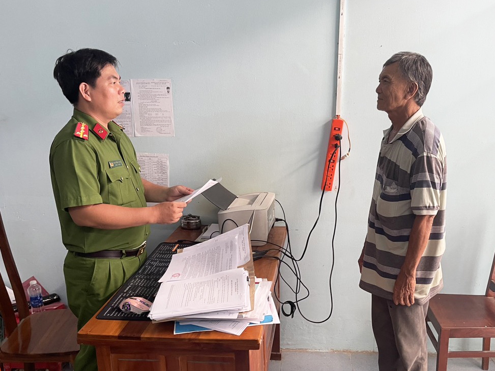 Đối tượng Hồ Văn Điều đang nghe cán bộ công an tống đạt các quyết định