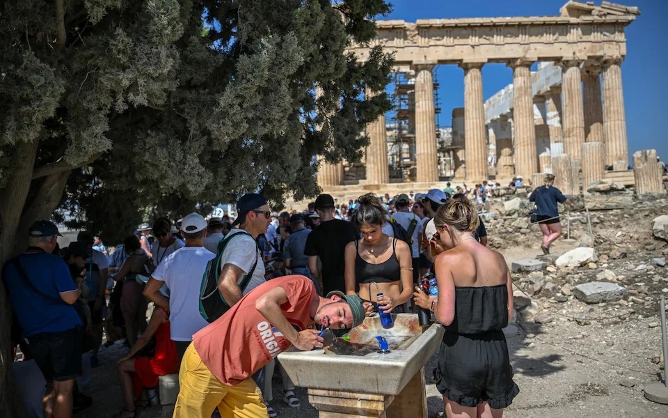 Khách du lịch giải nhiệt tại đài phun nước ở Athens trong đợt nắng nóng gay gắt (Ảnh: telegraph.co.uk)