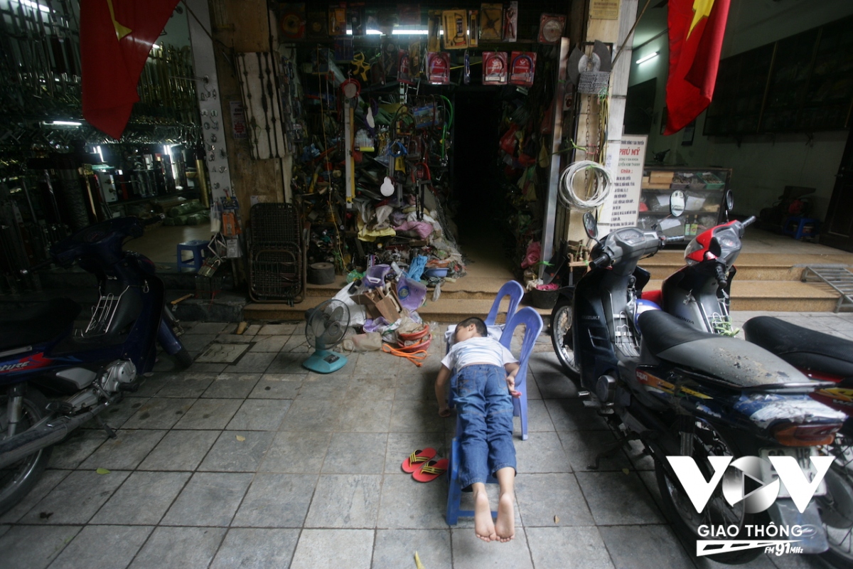 Cậu bé ngủ vùi trước cửa nhà "quên" cả việc trông hàng cho bố mẹ giữa trưa hè trên phố Lãn Ông