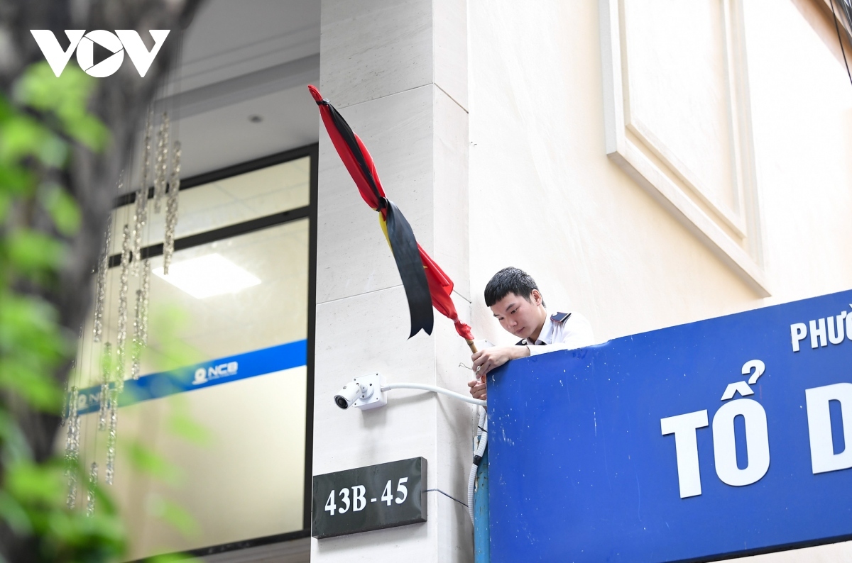 A local resident hangs the flag at half-mast on Quan Thanh street.