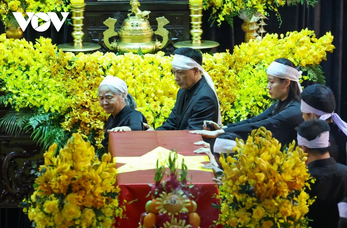 Man and her children touch the leader’s flag draped coffin at the funeral service on July 25 morning