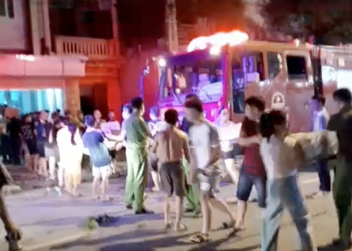 Hàng chục người dân cùng lực lượng chức năng đứng thành hàng dài di chuyển đồ đạc, hàng hoá ở dãy nhà gần hiện trường vụ cháy.