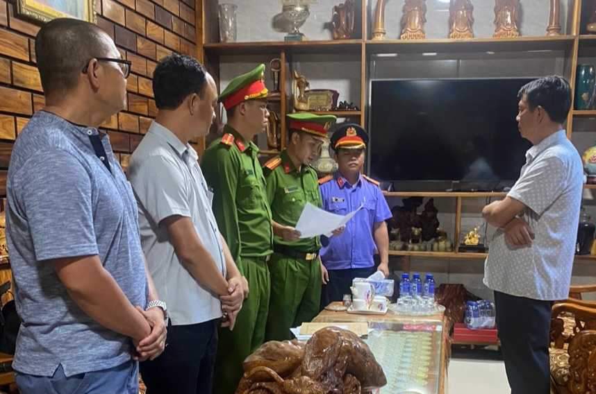 Ông Lê Quang Thuận (bìa phải) nghe Công an đọc Quyết định khởi tố bị can