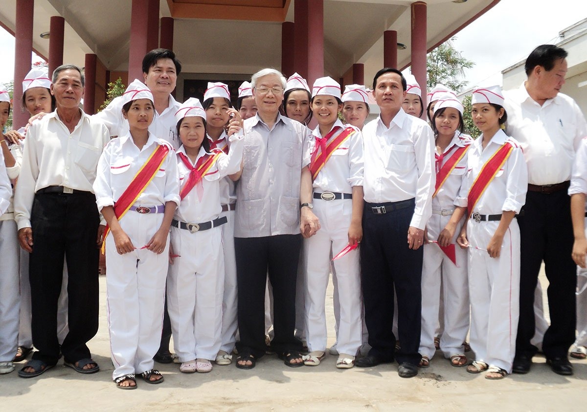 Tổng Bí thư chụp ảnh lưu niệm với cán bộ và các em học sinh huyện Bình Đại.