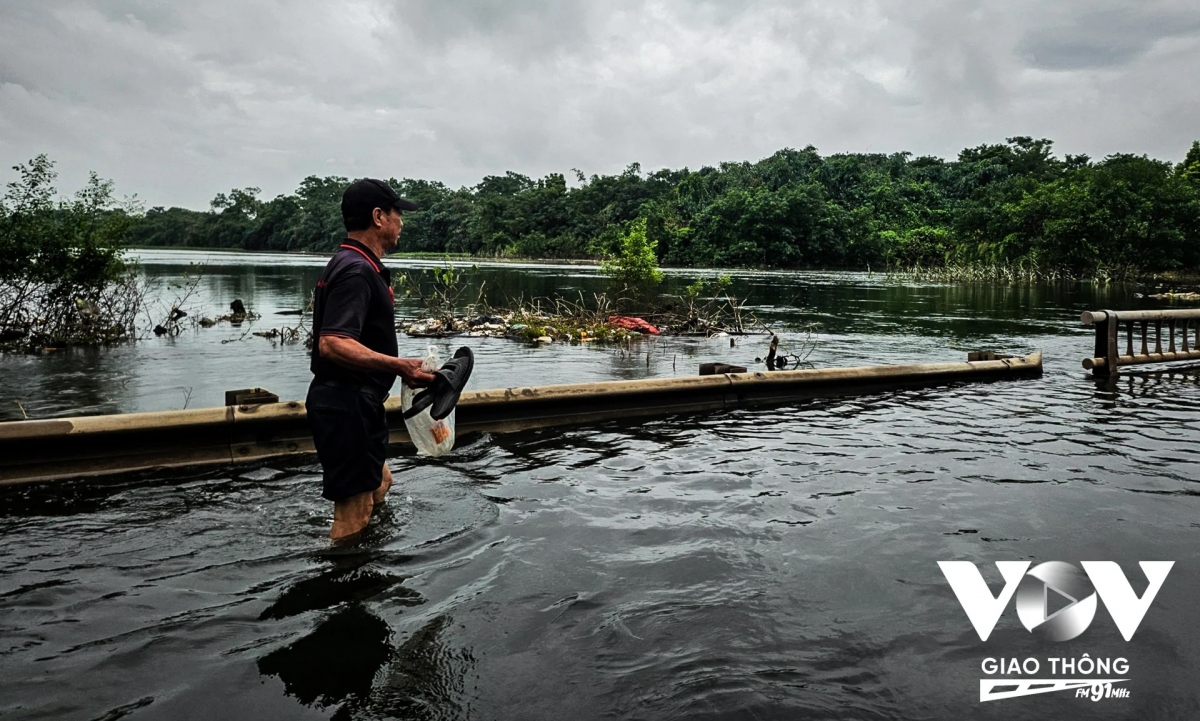 Một người đàn ông "xách dép qua cầu" để sang huyện Quốc Oai mua đồ dùng. Đến thời điểm sáng 30/7, mực nước tại cầu 72 II đã rút xuống 40cm. Các phương tiện ô tô nếu muốn di chuyển qua cũng có thể 'đi tạm'