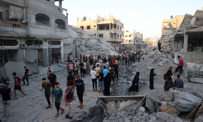 Người dân Palestine kiểm tra một tòa nhà bị Israel không kích tại trại tị nạn Nuseirat ở miền Trung Gaza hôm 22-8. Ảnh: AFP