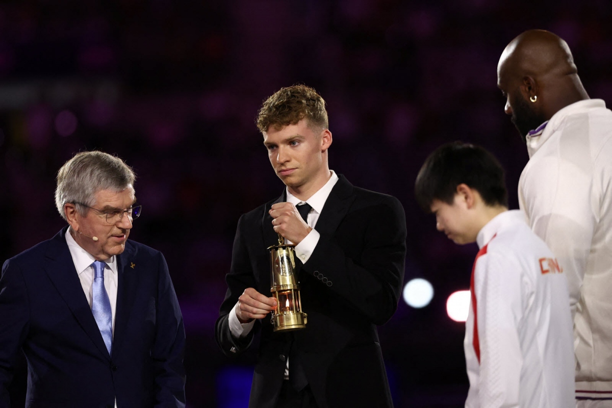Kình ngư Leson Marchand, người đã đạt nhiều huy chương Vàng tại Thế vận hội Olympic 2024, mang ngọn lửa Olympic đến sân Stade de France. (Ảnh: Le Progrès)