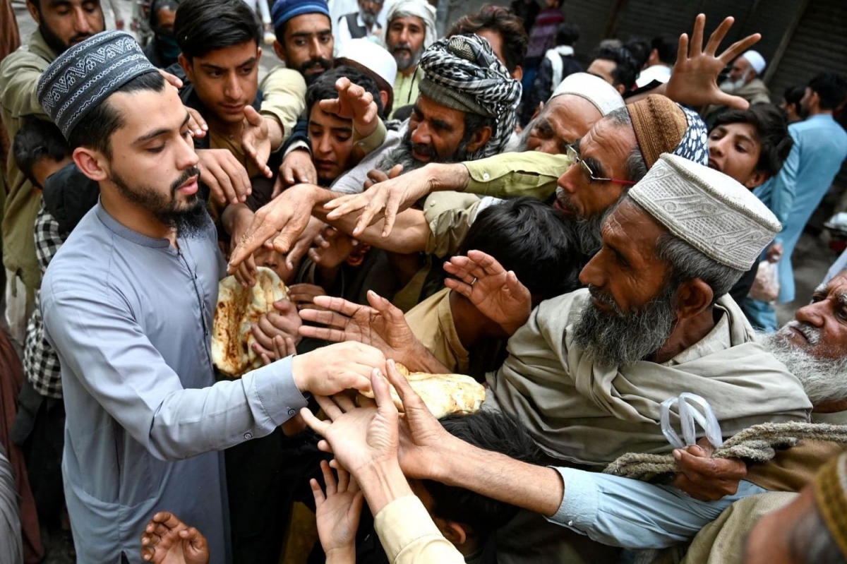 Người dân tại thành phố Peshawar, Pakistan nhận đồ ăn miễn phí tại một điểm phân phát hồi tháng 4/2023 (AFP).