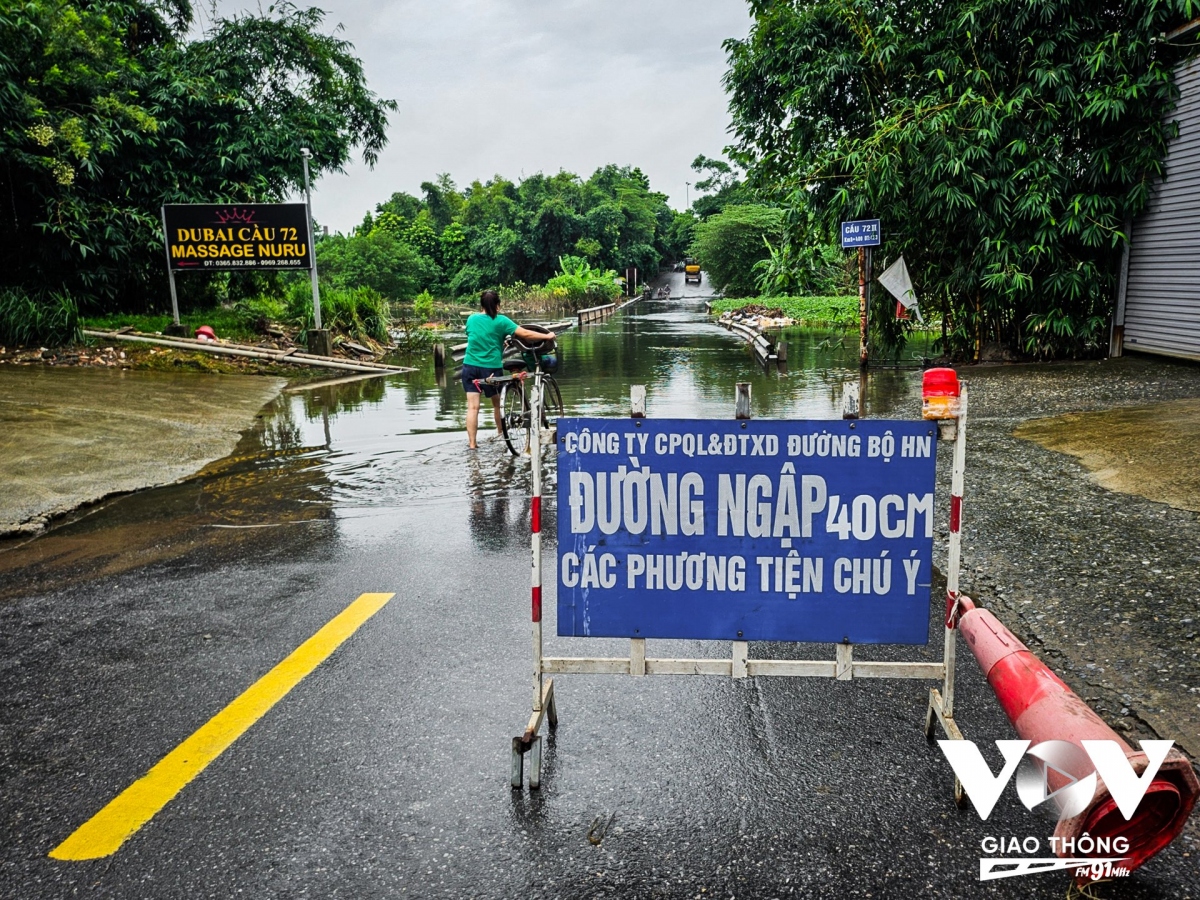 Theo ghi nhận của PV VOV Giao thông vào sáng 30/7, tại đoạn cầu 72 II thuộc địa phận xã Cộng Hòa (giáp ranh giữa 2 huyện Hoài Đức và Quốc Oai) vẫn ngập sâu 40cm. (Ảnh: Lực lượng chức năng đặt biển cảnh báo lượng nước vẫn còn ngập trên cầu)