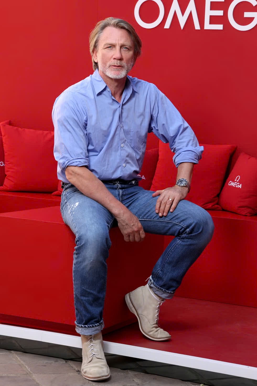 Daniel Craig đã chọn áo sơ mi xanh, quần jeans cổ điển và đồng hồ Omega.