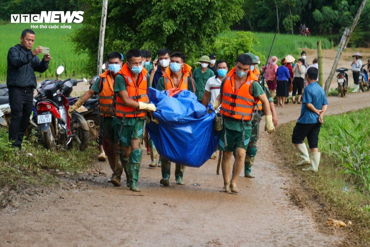 The soldiers continuously work together to carry the deceased up the slope halfway through the village for forensic examination and to hand over to their families for burial.