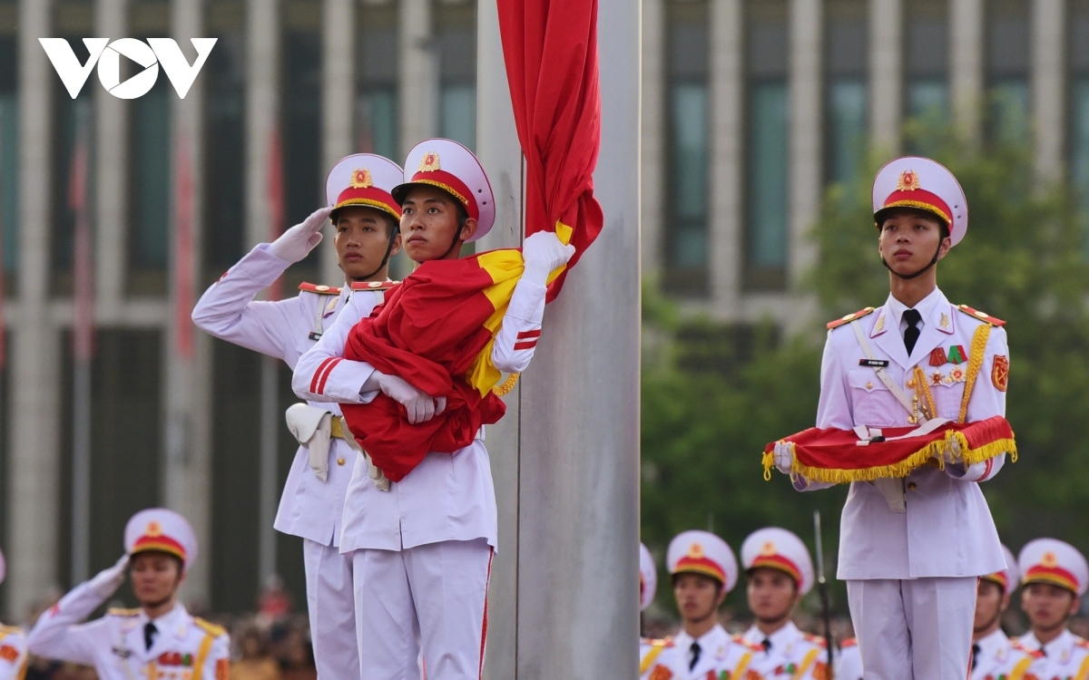 The soldier holds the red flag as he waits for the command and the commencement of the national anthem.