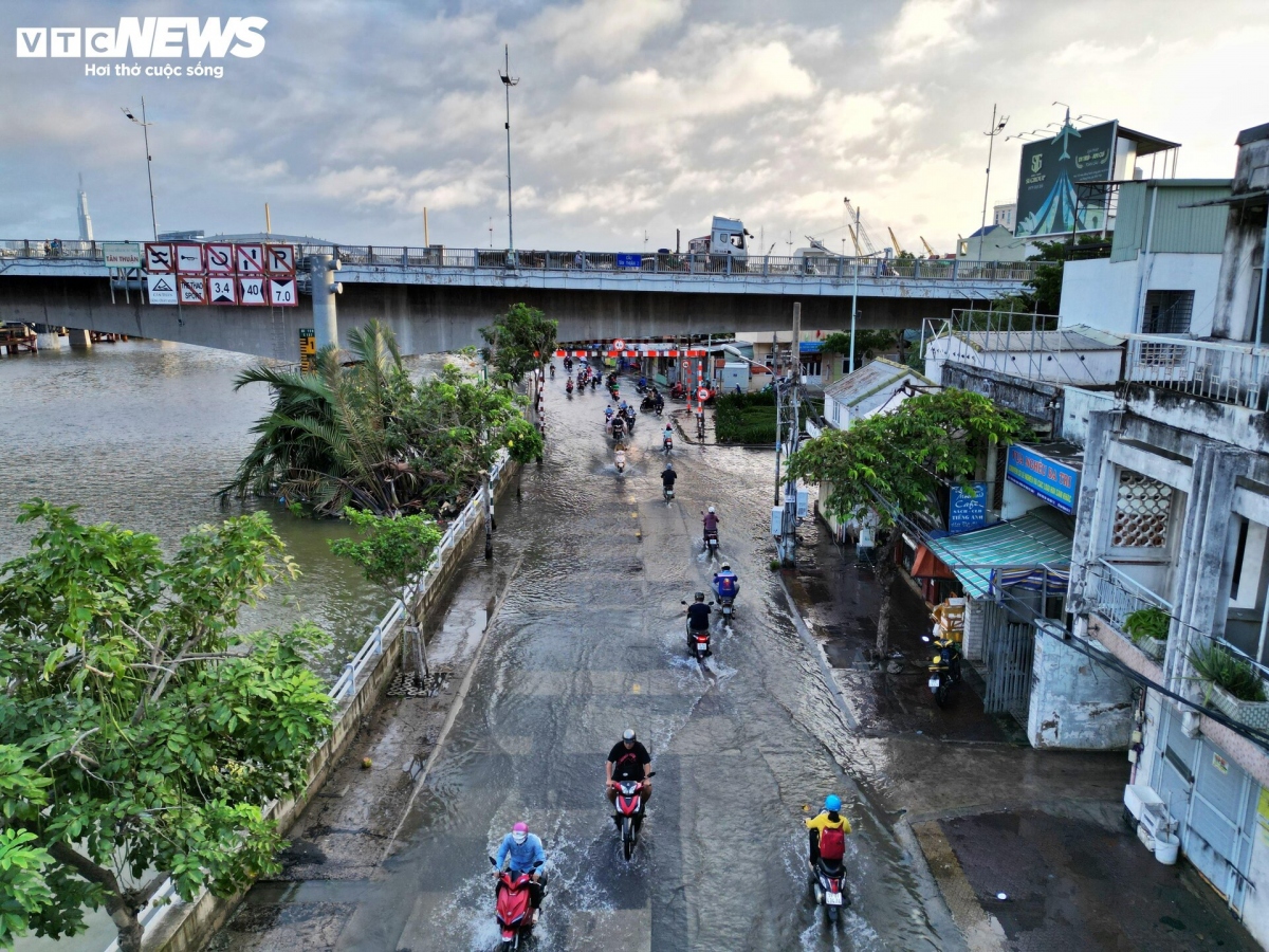 Commuters travelling to work and school on Tran Xuan Soan street endure difficulties as they try to cope with the rising water levels.