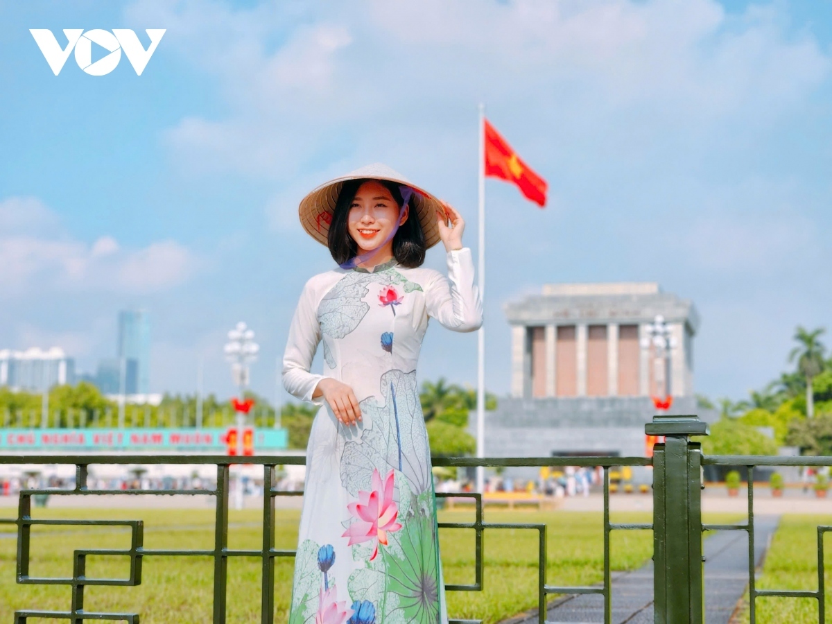 A woman wearing an Ao Dai poses for a photo as she wants to save the memories of the special occasion.