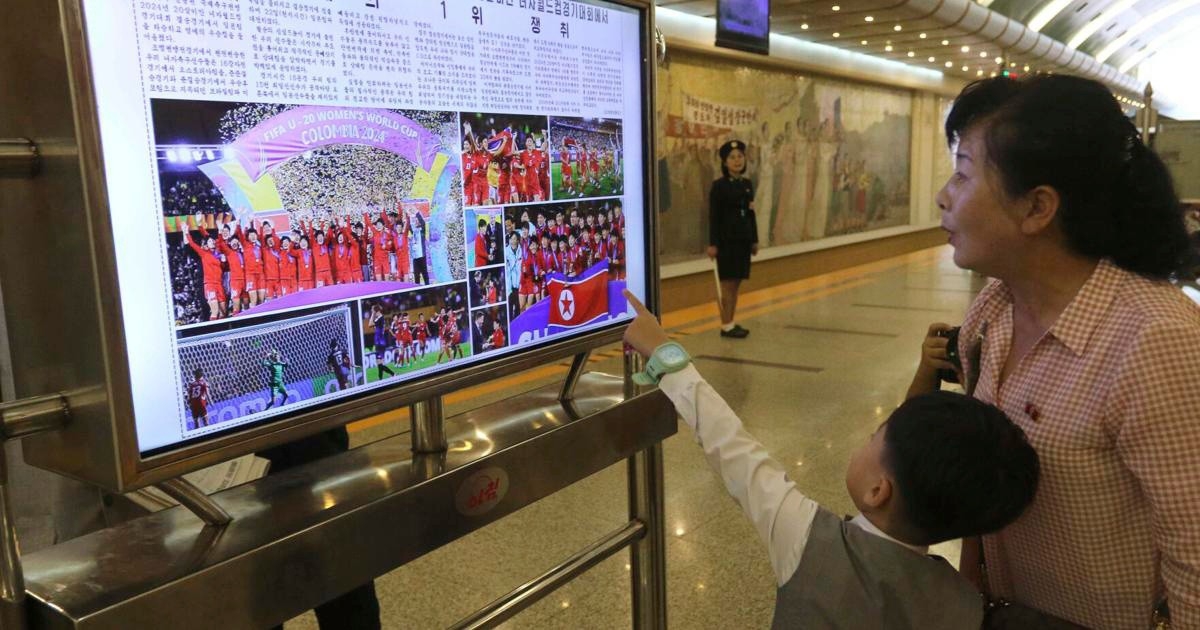 Trước đó, thông tin U20 nữ Triều Tiên vô địch U20 World Cup nữ 2024 đã được đăng tải rộng rãi trên các phương tiện truyền thông ở Triều Tiên. Trong ảnh là một phụ nữ cùng cậu con trai đang xem thông tin về chức vô địch của U20 nữ Triều Tiên khi ở ga tàu điện ngầm. 