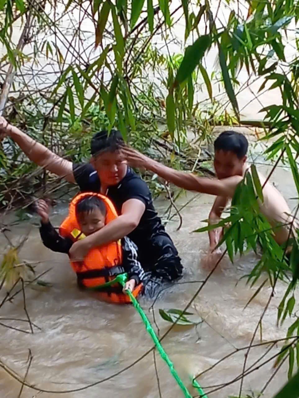 Đại uý Lục Văn Nguyên (áo đen) và anh Liệu Văn Quyết đưa cháu Bảo vào bờ an toàn.