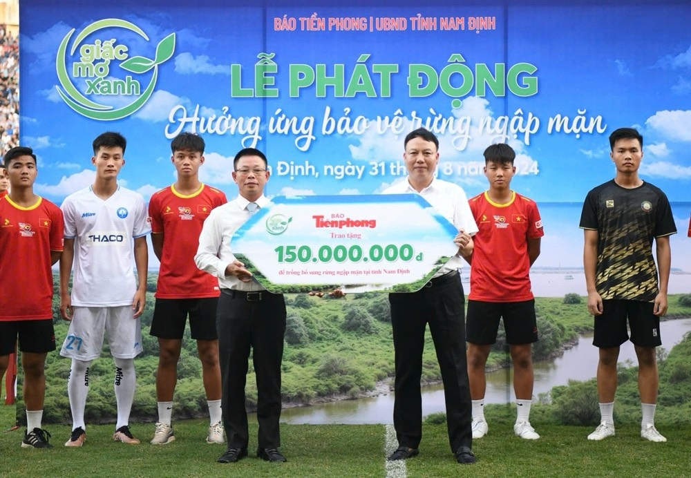 Nhà báo Phùng Công Sưởng - Tổng biên tập báo Tiền Phong, đồng Trưởng ban Tổ chức trận Siêu Cúp bóng đá Quốc gia 2023/2024 trao tặng tượng trưng cây trồng trị giá 150 triệu đồng cho ông Mai Quang Tuấn - Chi Cục trưởng Chi cục Kiểm lâm, đại diện Sở Nông nghiệp và Phát triển nông thôn Nam Định.