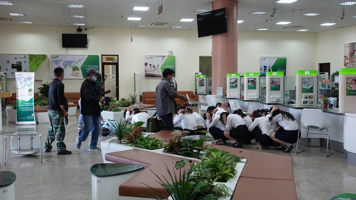Các đối tượng uy hiếp, khống chế bảo vệ và nhân viên ngân hàng. Ảnh: CABT 