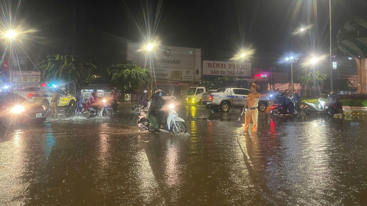 Lực lượng chức năng hướng dẫn người dân tránh đi đường ngập (ảnh: ĐC)