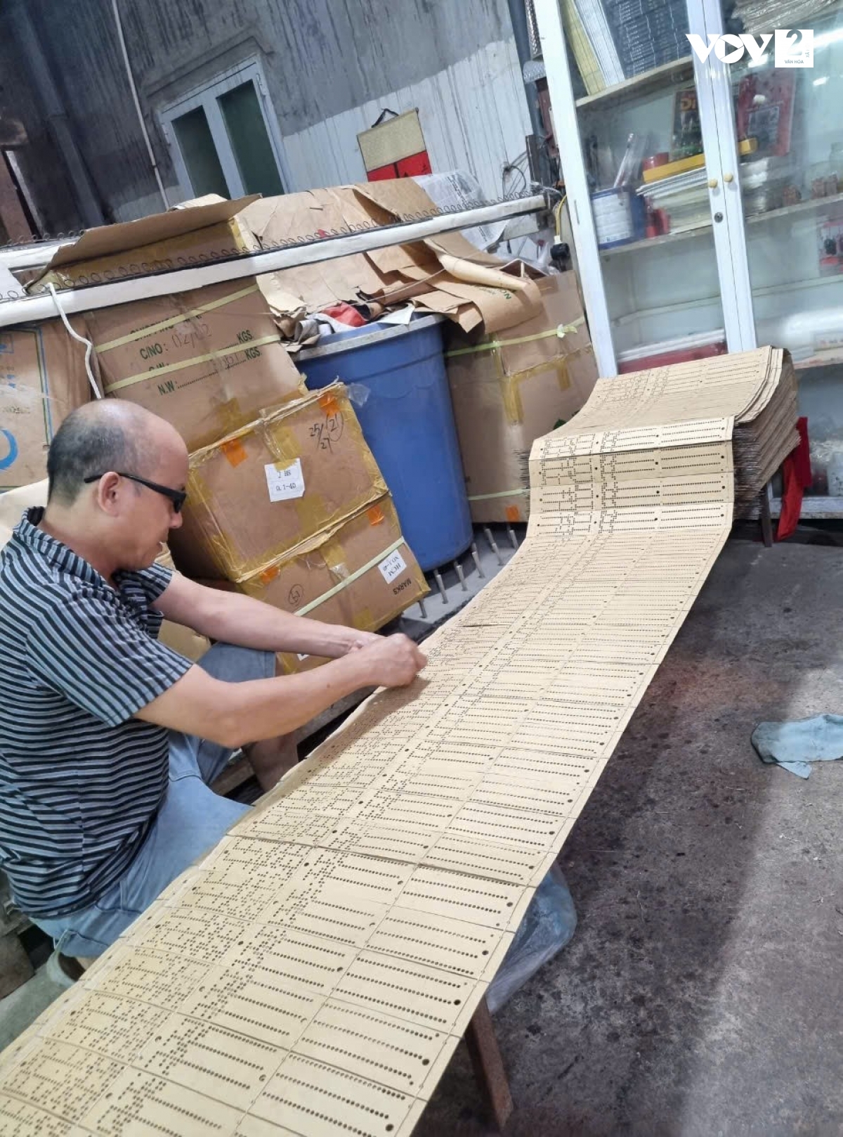 Nghệ nhân Lê Đăng Toản vẽ hoa văn đục bìa và khâu những miếng bìa đó lại với nhau cho máy dệt