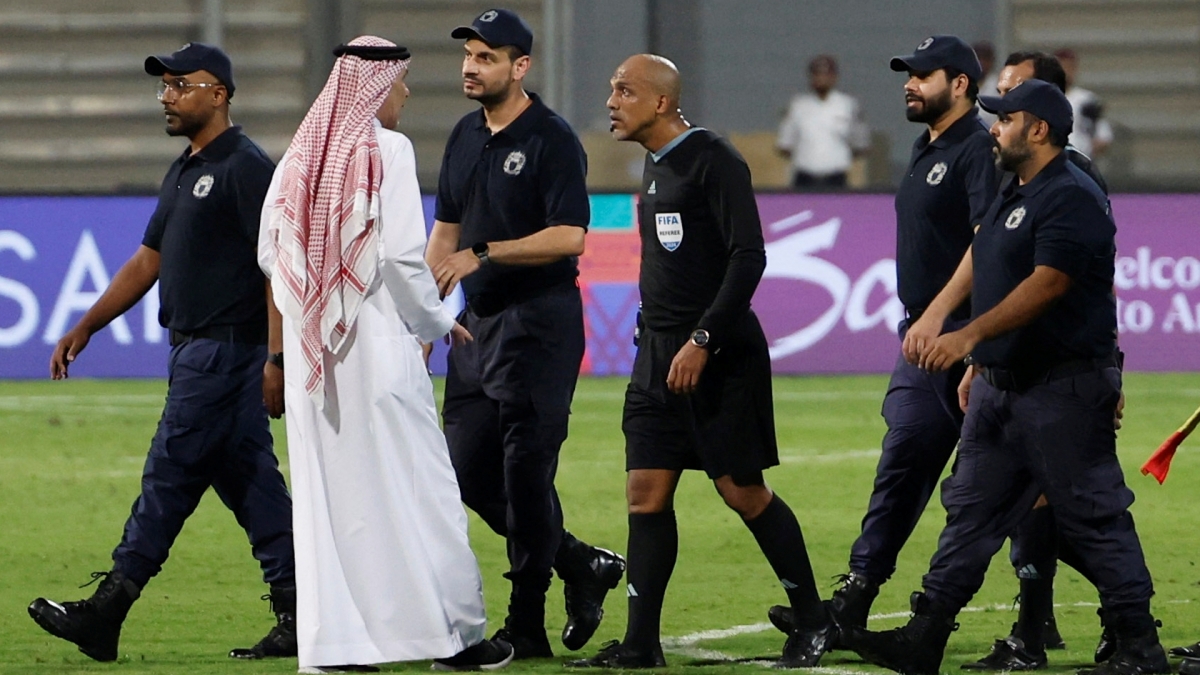 Trọng tài Ahmed Al Kaf được nhân viên an ninh hỗ trợ rời sân ở trận Bahrain 2-2 Indonesia (Ảnh: Reuters).