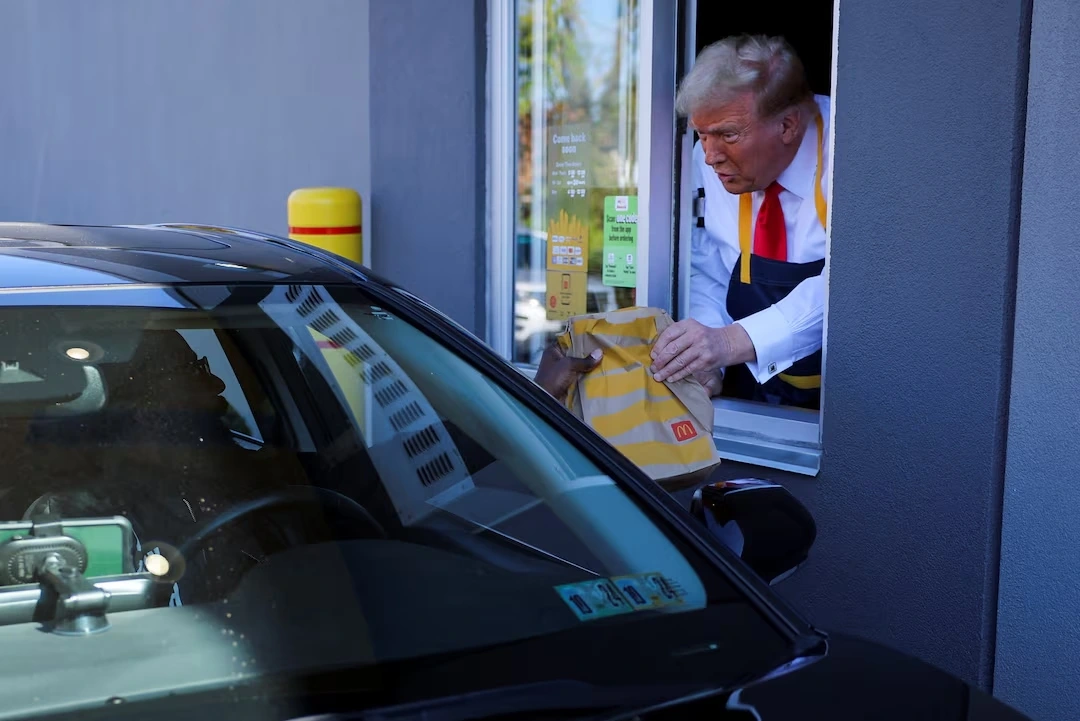 Ông Trump giao đồ ăn cho khách qua cửa sổ. Ảnh: Reuters