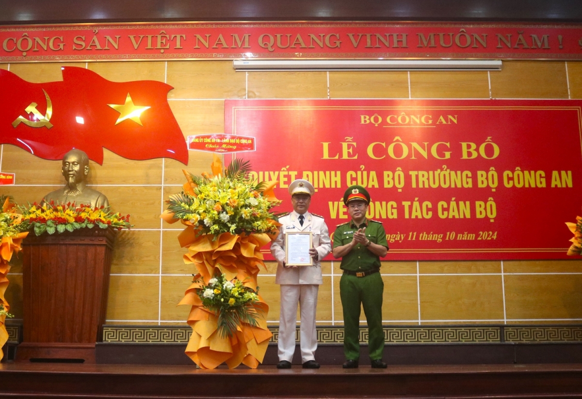 Trung tướng Nguyễn Văn Long (bên phải), Thứ trưởng Bộ Công an trao quyết định và tặng hoa chúc mừng Đại tá Nguyễn Thanh Liêm