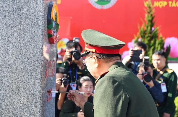 In a formal ceremony, both ministers salute and repaint a border marker.