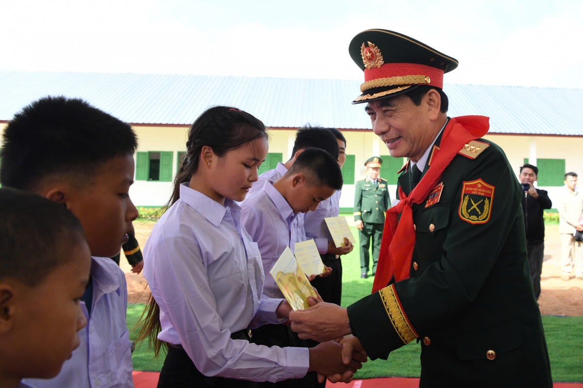  Đại tướng Phan Văn Giang khẳng định, Việt Nam và Lào là hai nước láng giềng, cùng uống chung dòng nước Mê Công, cùng tựa lưng vào dãy Trường Sơn hùng vĩ. Trải qua những thăng trầm của lịch sử, mối quan hệ thủy chung, trong sáng Việt Nam - Lào được Chủ tịch Hồ Chí Minh, Chủ tịch Kaysone Phomvihane và Chủ tịch Souphanouvong đặt nền móng, vun đắp đã không ngừng phát triển lên tầm cao mới. Mối tình đoàn kết đặc biệt và hiếm có này chính là tài sản vô giá của hai dân tộc mà thế hệ trẻ hai nước, trong đó có các học sinh Trường Tiểu học - Trung học cơ sở Pahang, sẽ tiếp tục gìn giữ và vun đắp, làm rạng rỡ thêm truyền thống đoàn kết gắn bó Việt Nam - Lào. Trong ảnh: Đại tướng Phan Văn Giang trao học bổng tặng các học sinh có hoàn cảnh khó khăn. 