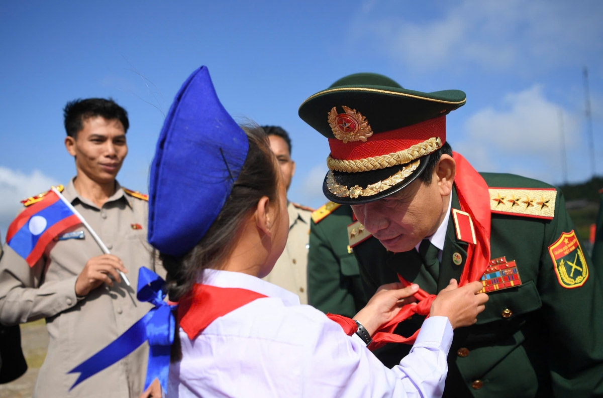  Đại tướng Phan Văn Giang vui mừng khi thấy các em học sinh mạnh khỏe, vui tươi, năng động, được học tập và lớn lên trong môi trường đầy tình yêu thương và sự quan tâm; lãnh đạo địa phương và Ban giám hiệu Nhà trường hết sức quan tâm, chú trọng đến việc tuyên truyền, giáo dục cho các em học sinh về mối quan hệ đoàn kết đặc biệt Việt Nam - Lào; thầy và trò nhà trường đã luôn khắc phục khó khăn về điều kiện địa hình, thời tiết, cơ sở vật chất để lan tỏa tri thức, gieo mầm tương lai. Trong ảnh: Đại tướng Phan Văn Giang xúc động đón nhận chiếc khăn quàng đỏ từ các cháu học sinh Trường Tiểu học - Trung học cơ sở Pahang.