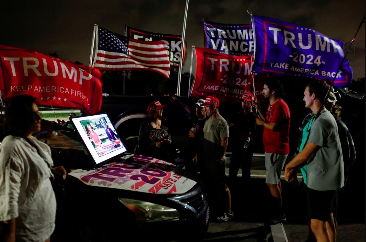 Những người ủng hộ ông Donald Trump theo dõi cập nhật kết quả bầu cử qua màn hình kết nối với một chiếc ô tô ngày 5/11 gần Mar-a-Lago ở Palm Beach, Florida.