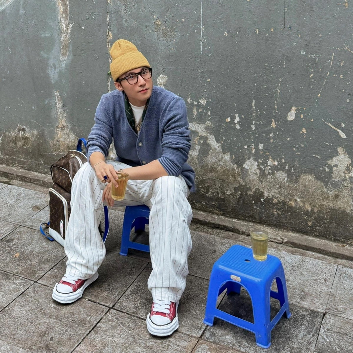 Mới đây, Sơn Tùng M-TP gây "sốt" khi ngồi uống trà đá vỉa hè ở Hà Nội. Dù ngồi ở vỉa hè, nam ca sĩ vẫn xuất hiện với bộ trang phục ấn tượng. Anh diện quần kẻ sọc với cardigan, áo thun, mũ vàng và giày sneaker, khoác ba lô Louis Vuitton.