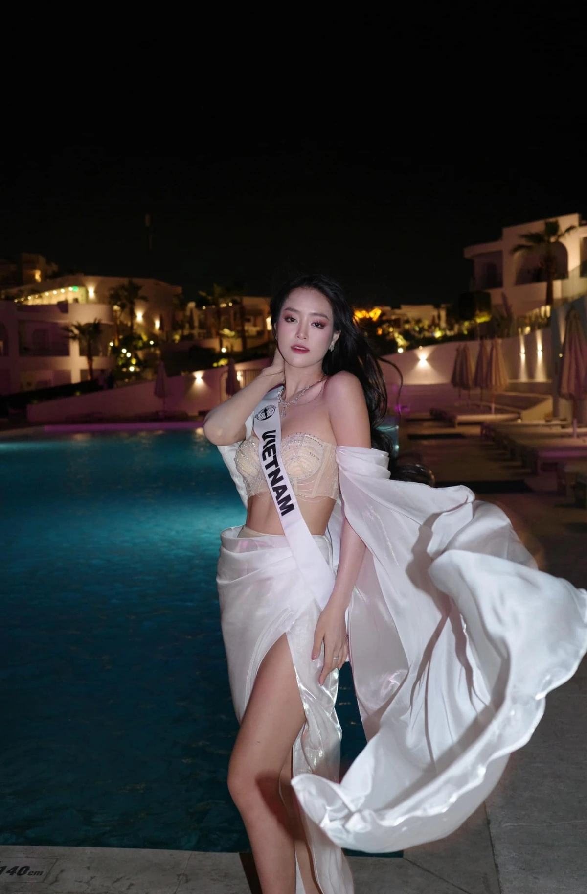 Trong một hoạt động vào buổi tối, người đẹp chọn thiết kế gồm hai mảnh tông be và trắng, phần trên là áo quây, phần dưới là váy xẻ cao. Bộ trang phục giúp Khánh Linh khoe trọn vóc dáng thon thả.